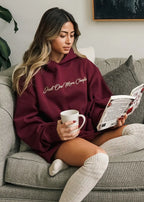 Woman in a maroon hoodie reading a book and holding a mug on a couch showing how relaxing and comfy the feel is.