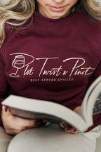 A woman wearing a maroon crew sweatshirt with 'Plot Twist & Pinot' in script text and underneath it reads "Best served chilled" in uppercase sans-serif font. 